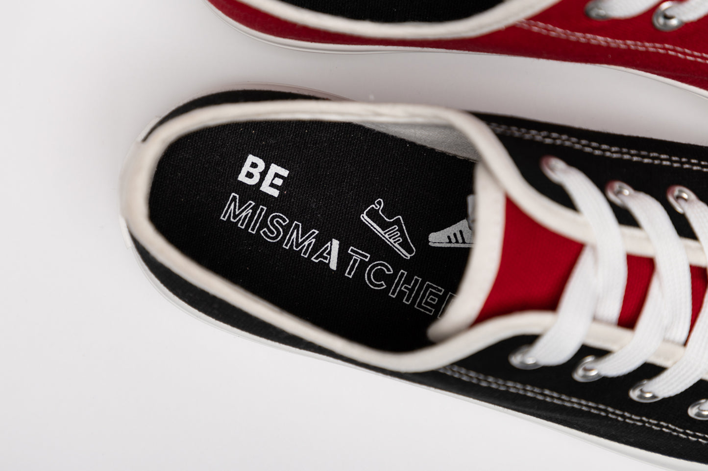 Close up top-down view of black mismatched sneakers with "Be Mismatched" Insole