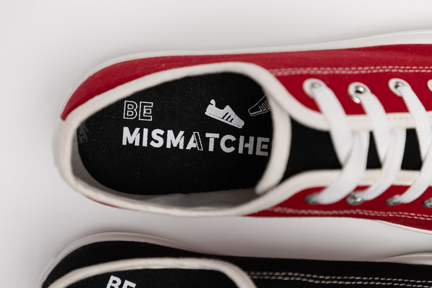 Close up top-down view of red mismatched sneakers with "Be Mismatched" Insole