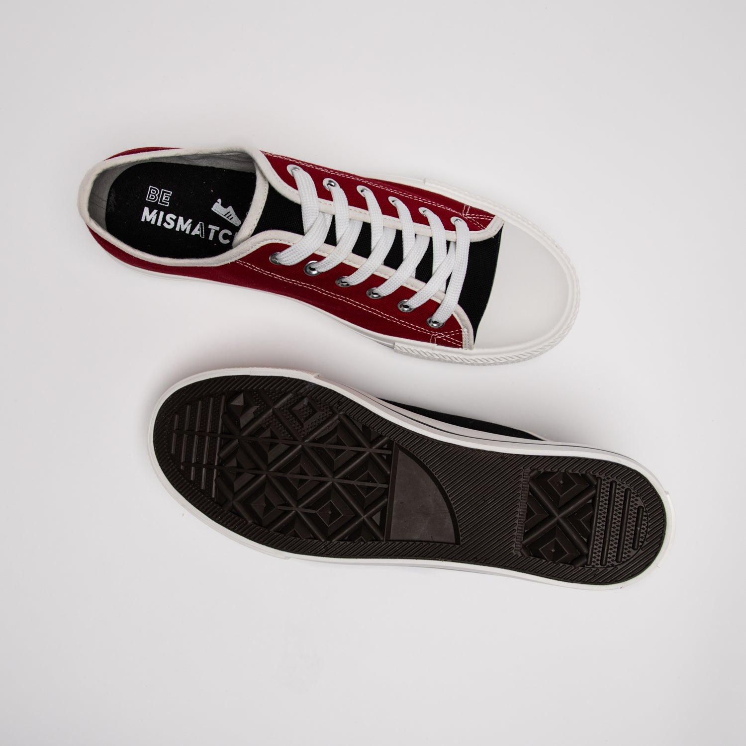 Top-down view of red mismatched sneaker face up and black mismatched sneaker face down, showing durable rubber sole